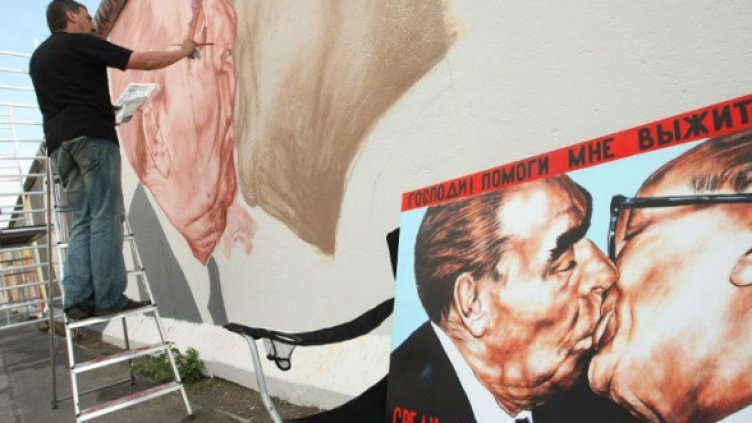 Руският художник Дмитрий Врубел рисува на Берлинската стена прословутата целувка на Леонид Брежнев и Ерик Хонекер.  Снимка: Getty Images/Guliver Photos