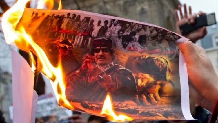 Протестиращи запалиха снимка на Муамар Кадафи по време на демонстрация в Париж. Снимка: БТА