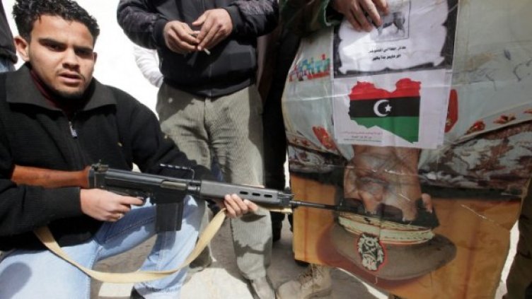 Либиец се цели в главата на Кадафи, нарисувана на плакат. Снимка: БТА