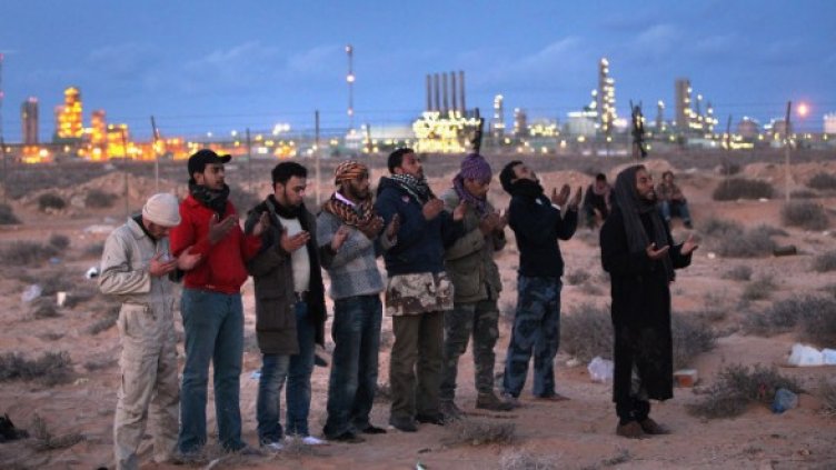 Либийски бунтовници се молят близо до петролните съоръжения в. гр. Рас Лануф. Опозиционните сили взеха под контрол стратегическия град в петък. Снимка: Getty Images/Guliver Photоs