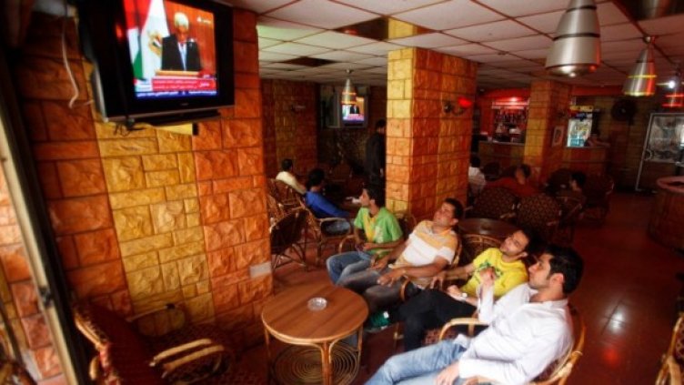Палестинци гледат по телевизията в кафене в Газа церемонията по подписването на споразумението между враждуващите фракции Фатах и Хамас в Кайро. Снимка: Reuters