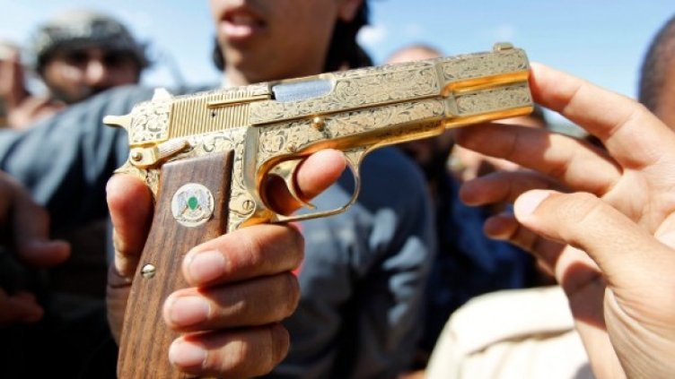 Боец от силите на новата либийска власт показва край Сирт златен пистолет, който бил на Муамар Кадафи. Снимка: Reuters