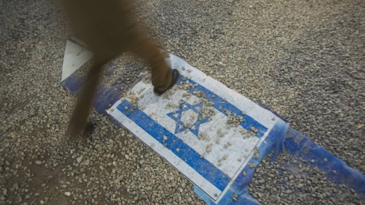 Иранец стъпва върху израелското знаме на изложба в Техеран по повод годишнината от иранско-иракската война. Снимка: Reuters
