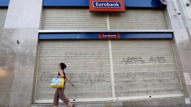 Жена минава покрай затворен банков клон в Атина. Снимка: Reuters