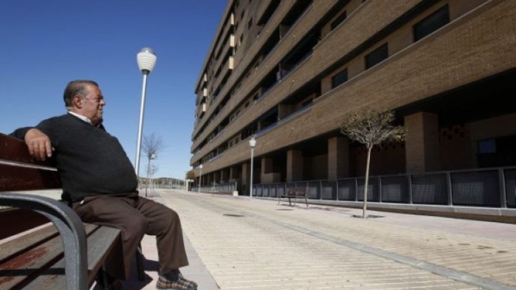 Възрастен мъж седи на пейка пред един от празните блокове в градчето Сесена. Снимка: Ройтерс