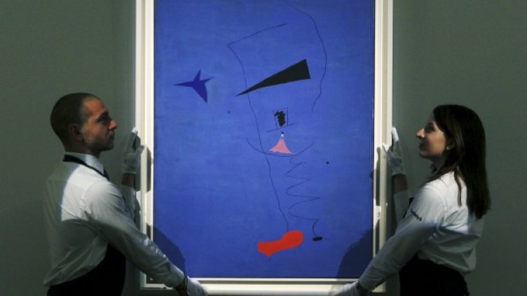 Галеристи подготвят за търга картината на Миро „Живопис (Синя звезда)“. Снимка: Reuters