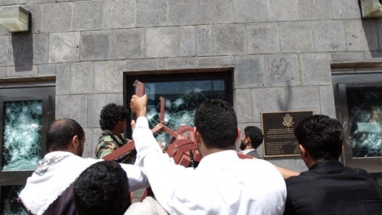 Протестиращи чупят стъклата на прозорци на сградата на посолството на САЩ в Сана. Снимка: Reuters