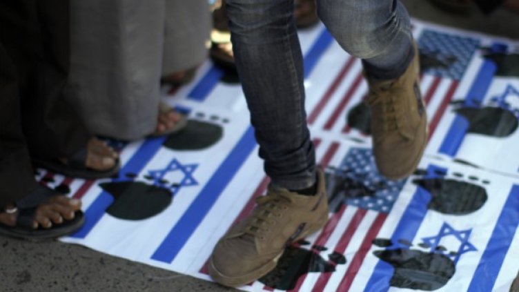 Протестиращи стъпват върху американското и израелското знаме в Сана, Йемен. Снимка: Reuters