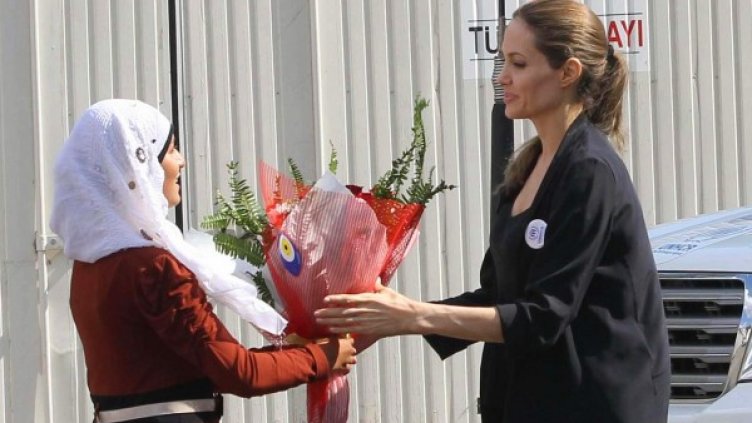 Сирийка поднася цветя на актрисата при посещението й в бежански лагер в турския град Килис. Снимка: Reuters