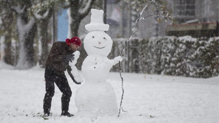 Мъж прави снежен човек край Берн, Швейцария. Снимка: БТА