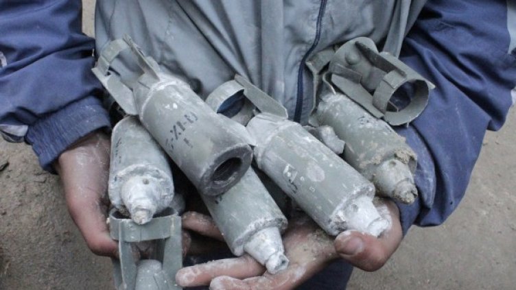 Мъж държи невзривени касетъчни бомби. Снимка: архив, Reuters