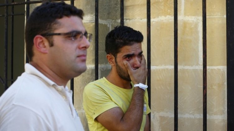 Спасен имигрант в Малта бърше сълзите си. Снимка: Reuters