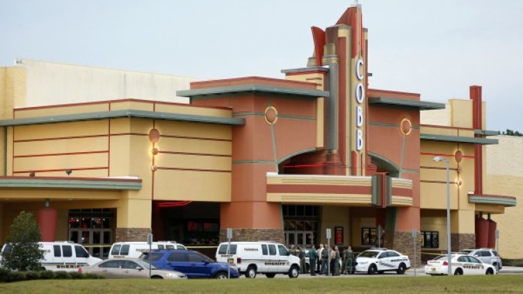 Полицейски служители пред киното, в което е извършено нападението. Снимка: архив Ройтерс