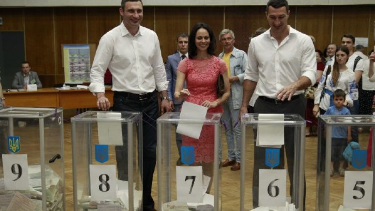 Спечелилият кметските избори в Киев Витали Кличко (ляво), съпругарта му и брат му Владимир (дясно), Снимка: Reuters