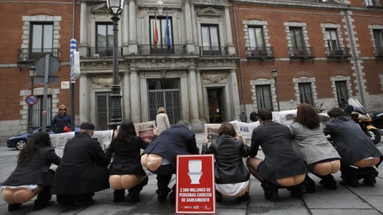 Активисти с гумени маски протестират символично пред външното министерство на Испания в Мадрид. Снимка: Reuters