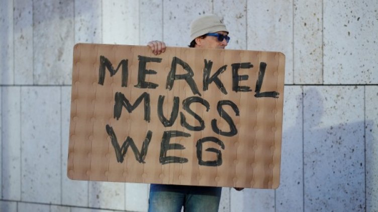 Протестиращ държи плакат с надпис "Меркел трябва да си ходи" пред централата на ХДС. Снимка: архив, Reuters