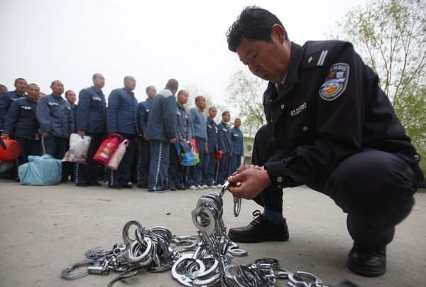 Полицай подрежда белезници, докато 600 затворници чакат да бъдат преместени в новата сграда на затвор в китайската провинция Хенан. Снимка: БГНЕС
&nbsp;