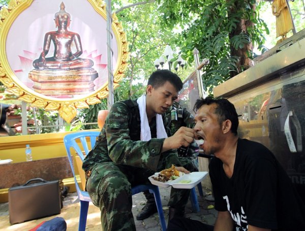 Тайландски войник храни арестуван представител на опозицията, която в продължение на седмици държеше под блокада центъра на града. Нахлуване на армията в лагера на протестиращите сложи край на обсадата на бизнес района на тайландската столица. Снимка: БГНЕС