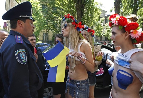 Полицаи се опитват да спрат протеста на украинска женска правозащитна организация. Активистките демонстрират в подкрепа на движението на  &bdquo;сините лампи&ldquo; в Русия. Руски шофьори слагат макети на сини лампи на автомобилите си в знак на несъгласие с арогантността на руски висши чиновници, които използват полицейски лампи, за да си проправят път. Сините лампи са се превърнали в символ на властващия елит. Снимка: БГНЕС