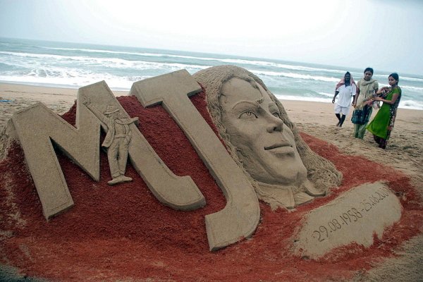 Хора стоят около пясъчна скулптура на Майкъл Джексън на плажа в Пури, Индия. Днес се навършва първата годишнина от смъртта на Краля на попа.Снимка: БГНЕС