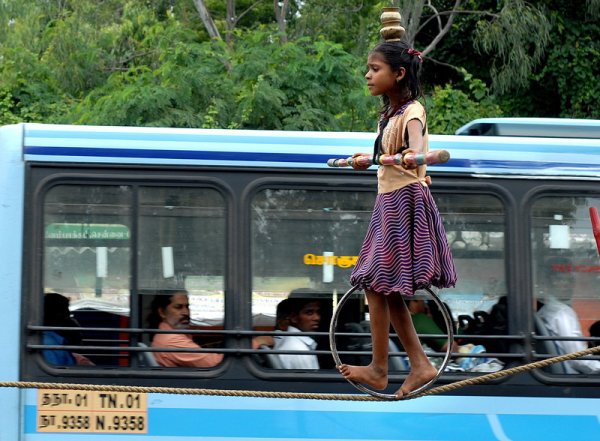 Индийско момиче показва акробатични номера на улица в Ченай, Индия. Тя и семейството й изкарват прехраната си, като пътуват от град на град и правят представления по улиците. Снимка: БГНЕС