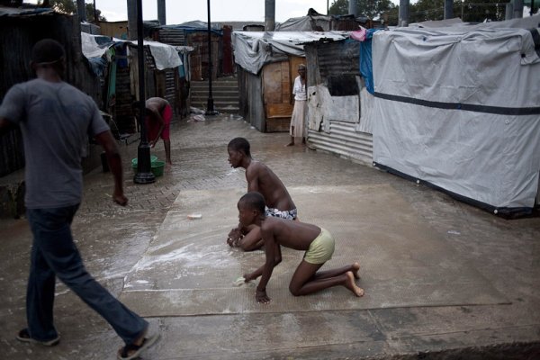 Хаитянски момчета перат килим в лагер в Порт-о-Пренс. Заразата от холера в страната взе 292 жертви. Здравните власти обявиха най-висока степен на тревога. Снимка: БГНЕС