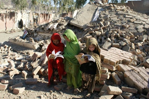 Пакистански ученички събират своите книги сред отломките на училището им, намиращо се близо до границата с Афганистан. Училището бе разрушено след бомбено нападение, вероятно дело на талибански бунтовници. Снимка: БТА