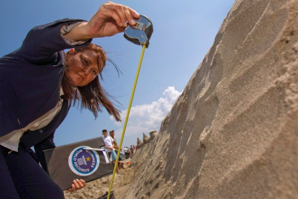 Представител на Гинес мери височината на стената, за да направи оцента на постижението. Снимка: Reuters