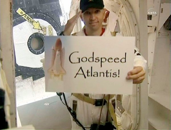 Друг член на екипажа държи лист, на който пише „Бог да благослови „Атлантис”. Снимка: Reuters