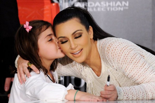 Американската телевизионна звезда Ким Кардашиян получава целувка от малко момиченце, докато раздава автографи в Сидни, Австралия. Снимка: БТА