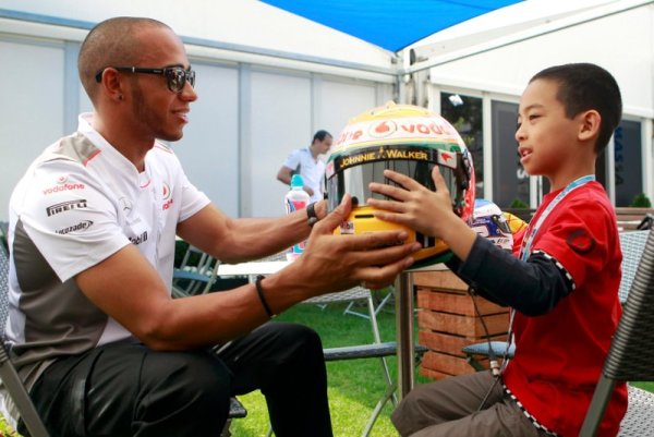 Друг световен шампион във Формула 1 &ndash; Люис Хамилтън, показва своята каска на момченце край бокса на МакЛарън. Снимка: Reuters