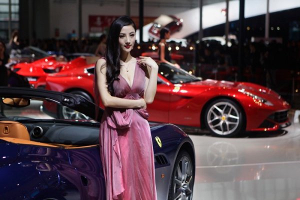 Китайска манекенка се снима пред модел на Ферари по време на автомобилното изложение в Пекин. Снимка: Reuters