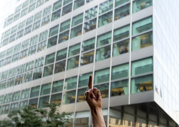 Протестиращ от движението "Окупирай Уол Стрийт" показва среден пръст пред сграда на американска корпорация. Снимка: Reuters