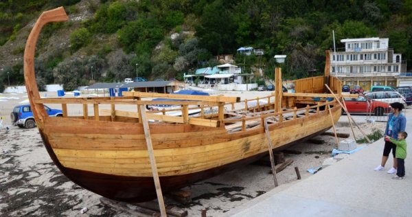 Туристи разглеждат дървена бойна галера, чието изграждане започнаха лодкостроители в Каварна. С такива лодки са плавали траките по моретата преди повече от 3 хил. години. Плавателният съд бързо се превърна в една от атракциите на плажа. Галерата е с дължина 17 метра, ширина 3 метра и ще разполага с мачта висока 8 метра и платно с площ 40 квадратни метра. Снимка: Impact Press Group
