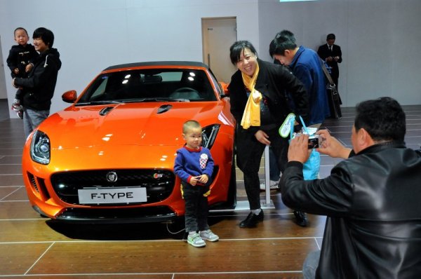 Малко дете и неговата майка позират за снимка пред Jaguar F-Type по време на автоизложение в китайската столица Пекин. Снимка: БТА