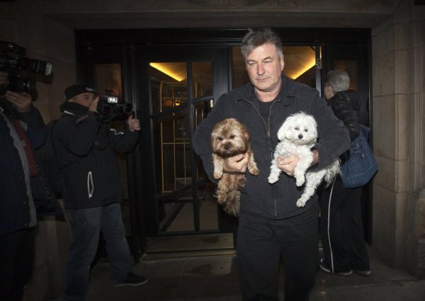 Актьорът Алек Болдуин излиза от апартамента си в Ню Йорк с две кучета под ръка. Той се забърка в скандал, след като замери с мобилен телефон репортер на местна медия. Снимка: Reuters