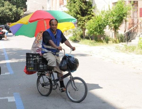 Изобретателен ром постави импровизиран покрив на велосипеда си в летния пек. Иновацията, съобразена с юлското слънце, всъщност е най-обикновен стар плажен чадър, прикачен към товарното отделение - пластмасова щайга. Снимка: Булфото &nbsp;
