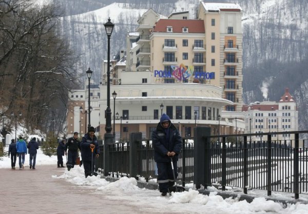 Работници чистят снега край хотели в Красная поляна. Топлото време и липсата на сняг се очертава като основен проблем пред организаторите. Снимка: Reuters