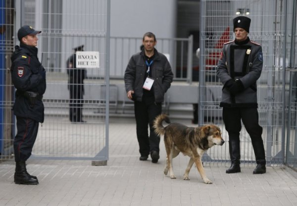 Бездомно куче преминава покрай охраната на железопътна гара в Сочи. Снимка: Reuters