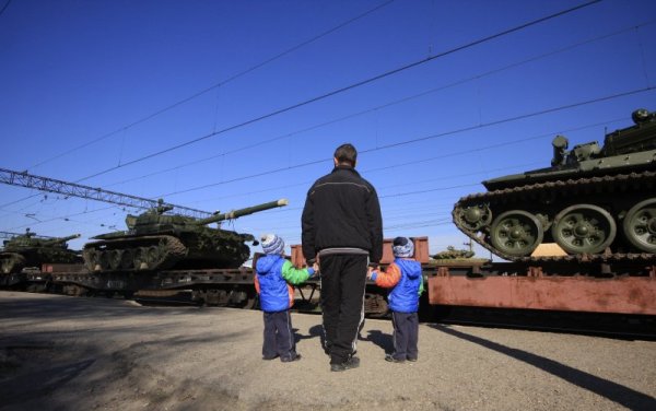 Мъж с двете си деца наблюдава пристигането на танкове в Крим. Снимка: Reuters