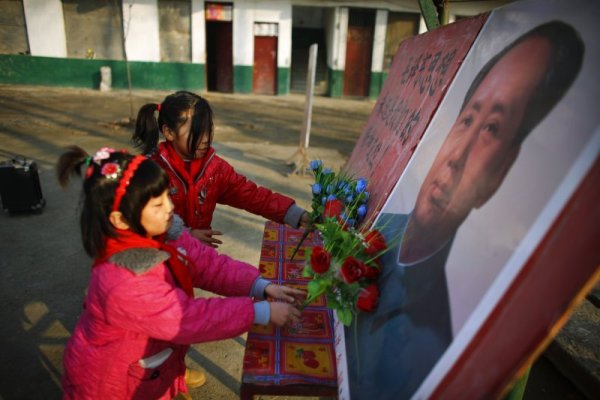 Ученици полагат изкуствени цветя пред портрета на Мао Дзедун. Снимка: Reuters