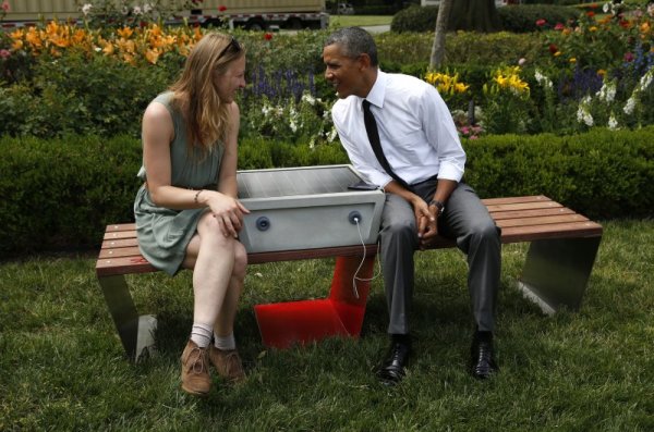 Екоразговор на дизайнерката Сандра Рихтер с президента на САЩ Барак Обама. Двамата са седнали на пейка, до уред със слънчеви батерии, който позволява да си заредят телефоните.  Снимка: Reuters