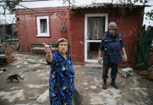 Местна жителка разказва на сапьор за случилото се, докато той проверява дома &#1117;. Снимка: Reuters