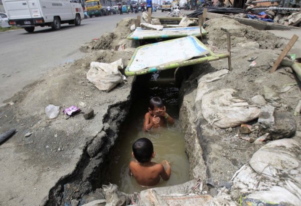 Деца си играят в мътните води на дренаж в Манила. Снимка: Reuters