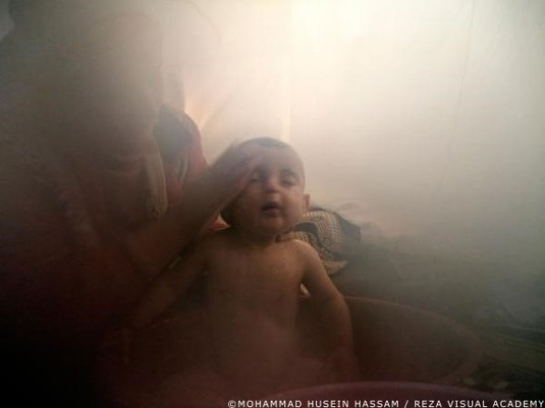 Майка къпе детето си в палатка в лагера Кавергоск Снимка: Мохамед Хюсеин, Reza Visual Academy