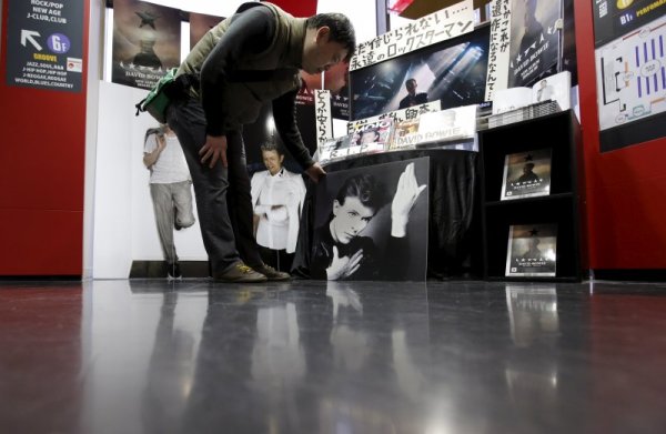 Японски фен гледа снимката на Бауи в Токио.  Снимка: Reuters