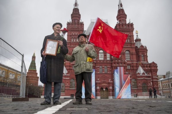 Двама руснаци държат портрет на Владимир Ленин и червен флаг, докато чакат да посетят Мавзолея на основателя на Съветския съюз Владимир Ленин. Днес се навършват 146 години от рождението на съветския лидер Снимка: БТА