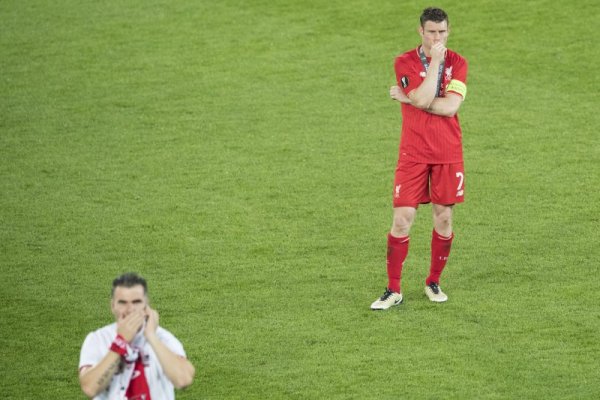 Капитанът на Ливърпул Джеймс Милнър гледа разочарован радостта на футболистите от Севиля след загубения финал в Лига Европа. Снимка: БТА