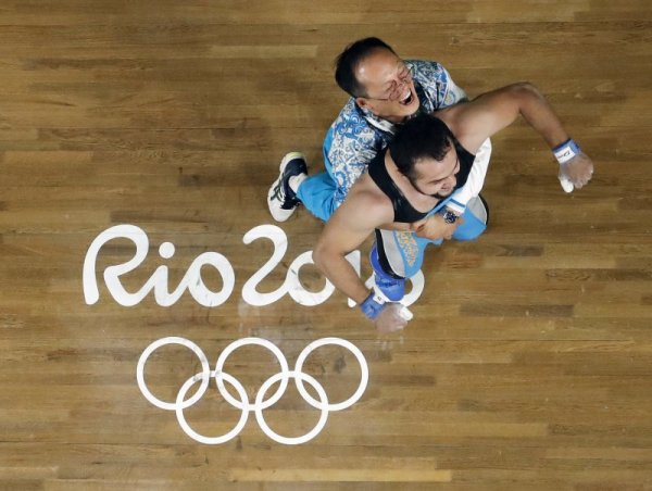 Треньорът на националния отбор на Казахстан по вдигане на тежести Алексей Ни е прегърнал своя състезател Нихат Рахимов, който току що е станал олимпийски шампион в категория до 77 килограма със световен рекорд в изтласкването. Снимка: БТА