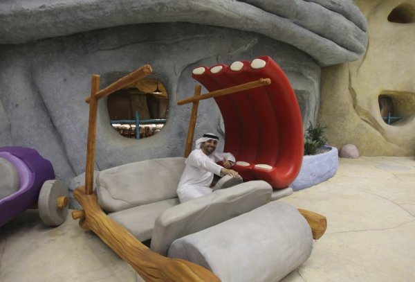 Мъж се радва на кола на Фред Флинстоун по време на откриването на увеселителен парк на Дисни в Абу Даби. Снимка: БТА